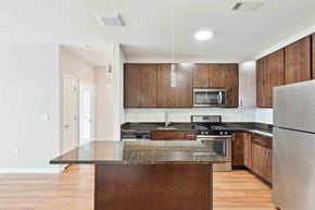 West Hempstead apartment for rent - a kitchen with dark wood cabinets and an island with granite countertops at West 130, New York