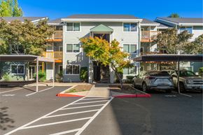 Aloha apartment for rent - A parking lot with cars and apartment buildings in the background.