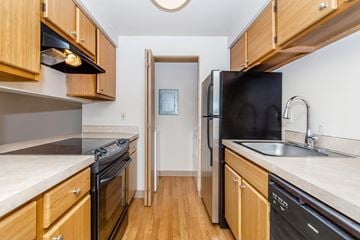 Tigard apartment for rent - A kitchen with wooden cabinets and a black refrigerator.
