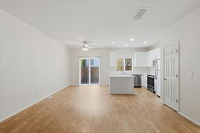 Aloha apartment for rent - A spacious room with wooden flooring and a ceiling fan.