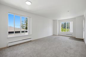 Portland apartment for rent - A spacious room with a carpeted floor and two windows.