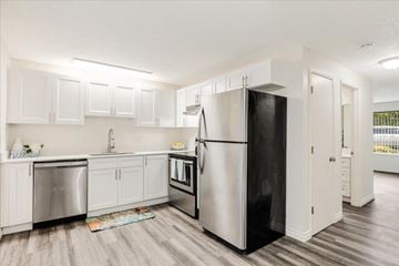 Milwaukie apartment for rent - A kitchen with a black refrigerator and white cabinets.