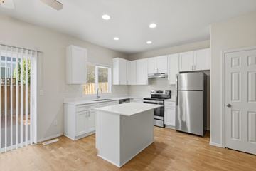 Aloha apartment for rent - A kitchen with white cabinets and a wooden floor.