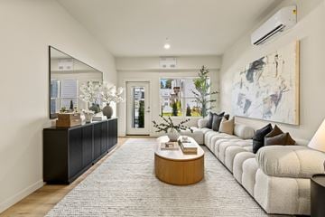Vancouver apartment for rent - A modern living room with a large mirror, a coffee table, and a large painting on the wall.