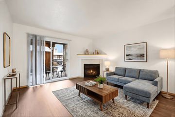 Portland apartment for rent - A living room with a grey couch, a coffee table, a fireplace, and a painting on the wall.