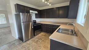 Portland apartment for rent - A kitchen with a stainless steel refrigerator and black cabinets.
