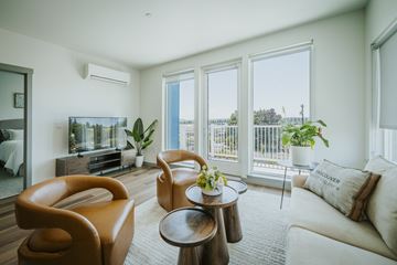 Vancouver apartment for rent - A living room with a brown leather chair and a white couch.