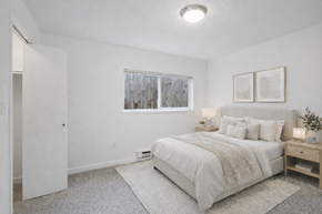 Beaverton apartment for rent - A bedroom with a large bed and a window with a view of trees outside.