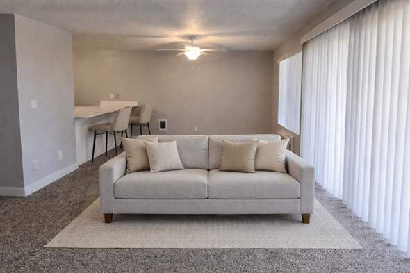 Milwaukie apartment for rent - A living room with a couch, a rug, and a table with chairs.