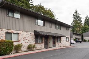 Vancouver apartment for rent - A building with a grey roof and a brick wall with a car parked in front.