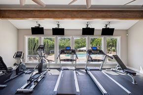Salem triplex for rent - A gym with treadmills, exercise bikes, and a ceiling fan.