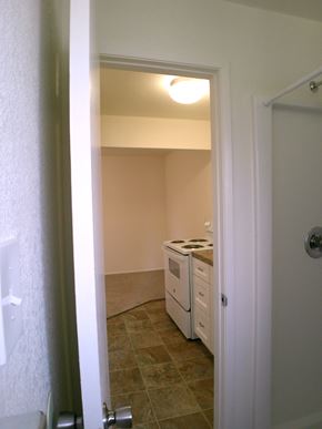 Seaside apartment for rent - A white door is open to a room with a stove and a counter.