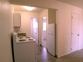 Seaside apartment for rent - A white stove is in a small room with a refrigerator and two doors.