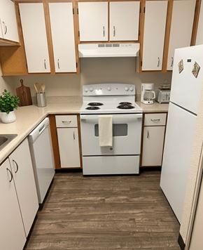 Hillsboro apartment for rent - A white stove and refrigerator in a kitchen with wooden cabinets.