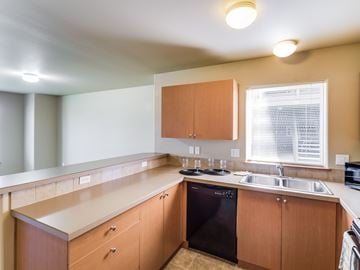 Redmond apartment for rent - A kitchen with wooden cabinets and a black dishwasher.