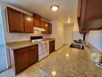 Beaverton apartment for rent - A kitchen with brown cabinets and a white stove top oven.