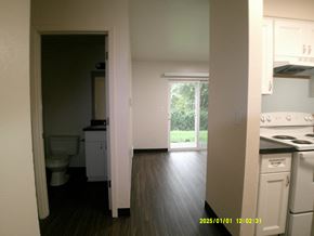 Hammond apartment for rent - A kitchen with a white fridge and a white toilet in a room with wooden floors.