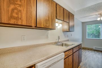 Aloha apartment for rent - A kitchen with wooden cabinets and a white dishwasher.