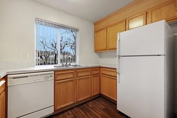 Portland apartment for rent - A kitchen with a white fridge, dishwasher and wooden cabinets.