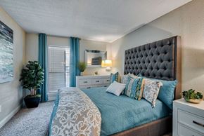 Houston apartment for rent - A bedroom with a large bed and a potted plant.