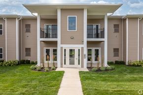 Northville apartment for rent - A building with a white roof and beige walls with a glass door and windows.