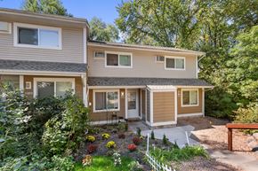 Plymouth apartment for rent - A house with a brown and beige exterior is surrounded by greenery and has a small garden in front.