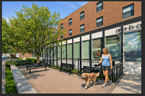 Minneapolis apartment for rent - A woman walking her dog in front of a brick building.