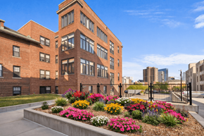 Minneapolis apartment for rent - A red brick building with a flower bed in front.
