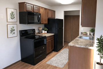 Eden Prairie apartment for rent - A black oven and microwave in a kitchen with brown cabinets.