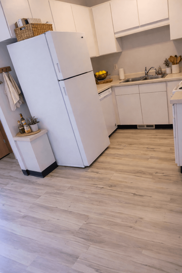 Crosby apartment for rent - A white refrigerator stands in a kitchen with wooden flooring.