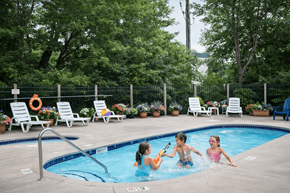 St. Louis Park apartment for rent - Three children playing in a pool surrounded by lounge chairs and greenery.