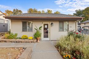 Prior Lake apartment for rent - A house with a brown roof and a grey door surrounded by plants and flowers.