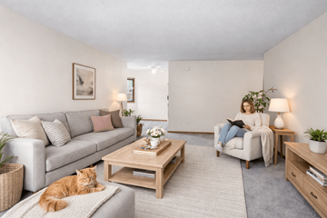 St. Louis Park apartment for rent - A woman is sitting on a couch in a living room with a cat lying on the floor.