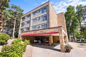 Wayzata apartment for rent - A building with a red awning and a parking lot in front.