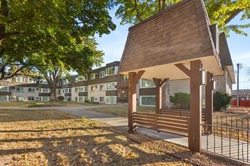 Minneapolis apartment for rent - A wooden pavilion sits in the middle of a grassy area with a fence and apartment buildings in the background.