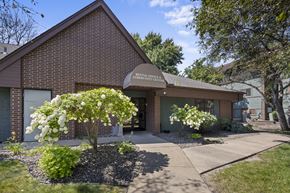 Brooklyn Park apartment for rent - the front of a brick building with a sidewalk and trees