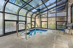 Hopkins apartment for rent - a indoor hot tub in a greenhouse with chairs and a wall of windows
