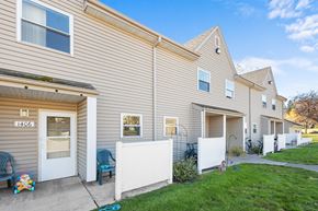 Two Harbors apartment for rent - A residential building with a white fence and a blue chair in front.