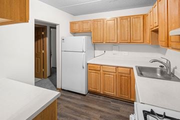 Hopkins apartment for rent - A kitchen with wooden cabinets and a white refrigerator.