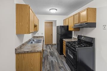 Brooklyn Park apartment for rent - A kitchen with black appliances and wooden cabinets.