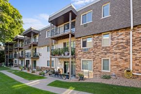 St. Louis Park apartment for rent - A row of multi-story apartment buildings with balconies and potted plants.