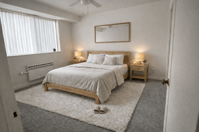 St. Louis Park apartment for rent - A bedroom with a large bed, a ceiling fan, and a window with blinds.