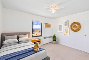 St. Louis Park apartment for rent - A cat is sitting on a bed in a bedroom with a ceiling fan.