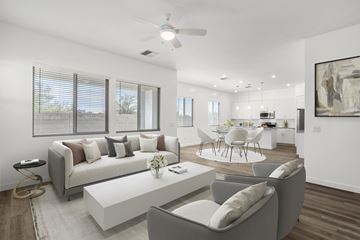 Mesa apartment for rent - A modern living room with a grey sofa, a white coffee table, and a dining table set up in the background.