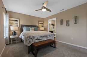 Aurora apartment for rent - A bedroom with a bed, bench, and a ceiling fan.