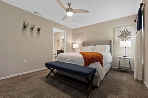 Battle Creek apartment for rent - A bedroom with a bed, a bench, and a ceiling fan.