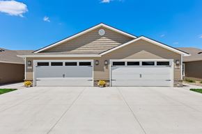 Bennington apartment for rent - A two-car garage with a tan house in the background.