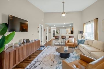 Brownsburg apartment for rent - A living room with a large couch, a coffee table, and a television mounted on the wall.