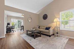 Brownstown apartment for rent - A living room with a couch, a table, a clock, and a window with blinds.