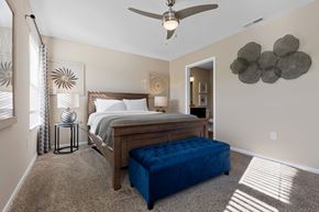 Brownstown Twp apartment for rent - A bedroom with a bed, a bench, and a ceiling fan.
